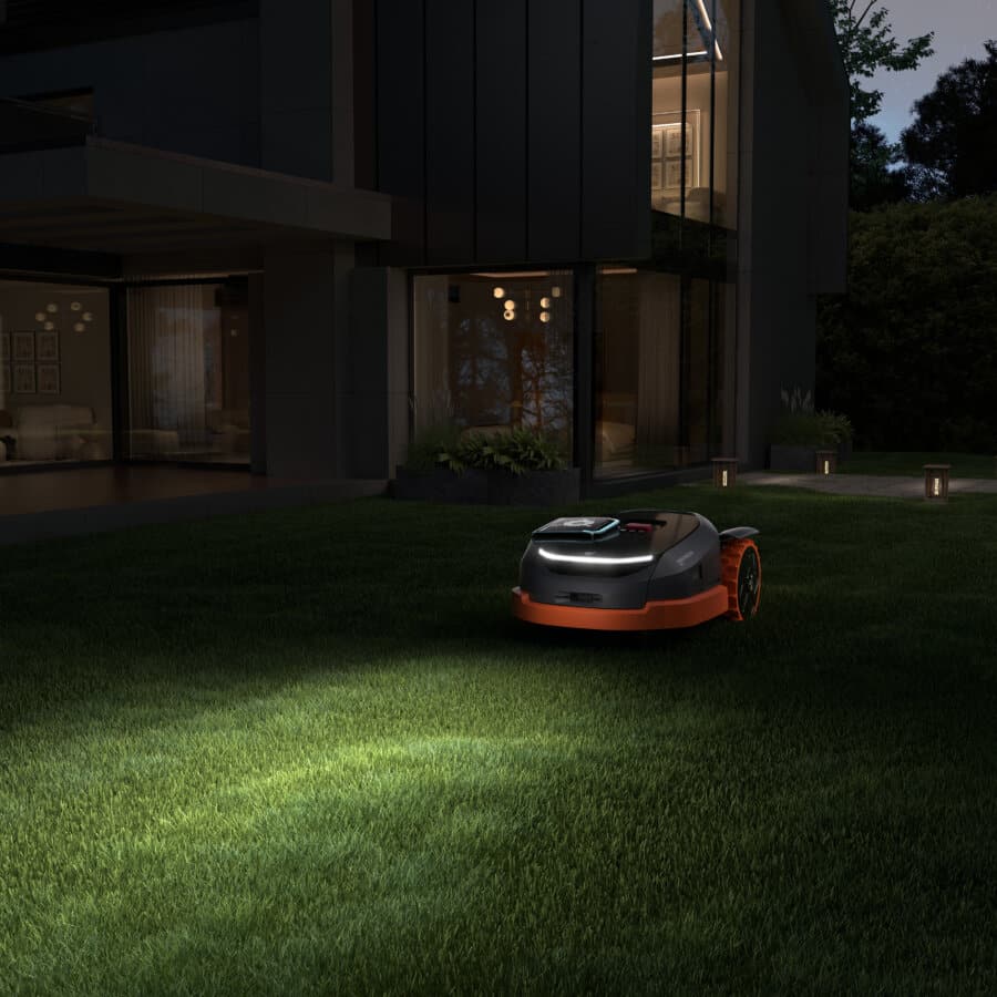 Segway Navimow X3 Serie Mähroboter bei Nacht im Garten eines modernen Hauses mit Beleuchtung